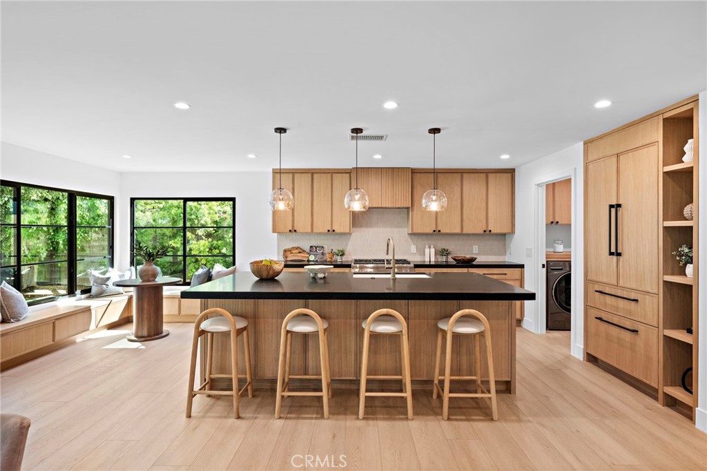 Kitchen with a large wood-paneled island, four stools, and expansive garden-facing windows.