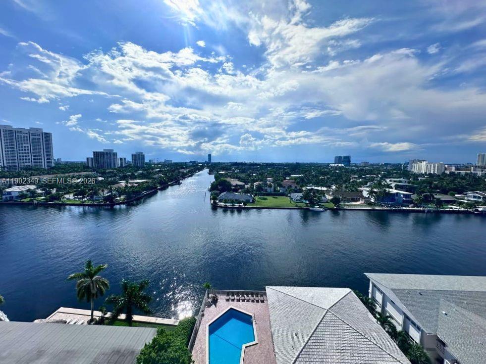 Waterway view from above, with a pool and neighboring rooftops in the foreground.
