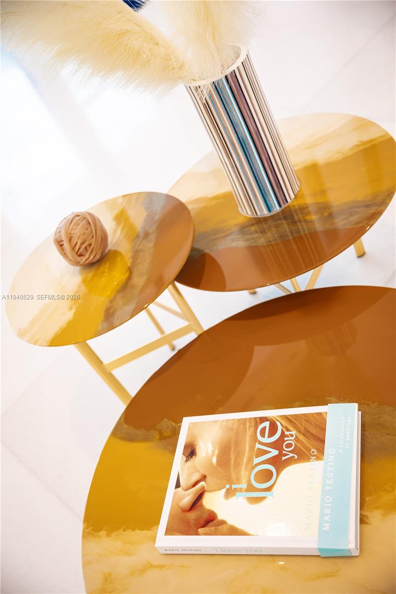 Glossy amber nesting tables with a Mario Testino book and a striped lamp with a fluffy shade.