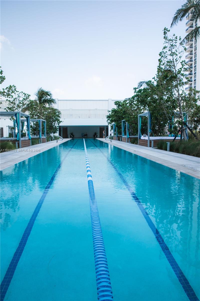 Outdoor lap pool with a central lane divider and landscaped seating areas.