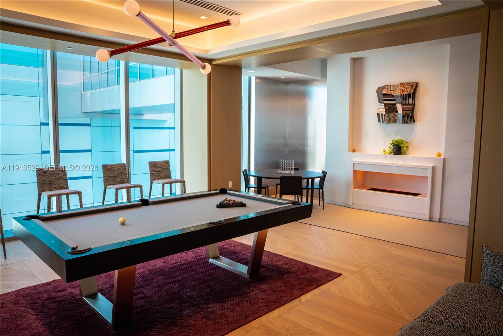 Game room with a billiards table, floor-to-ceiling windows, and a modern fireplace.