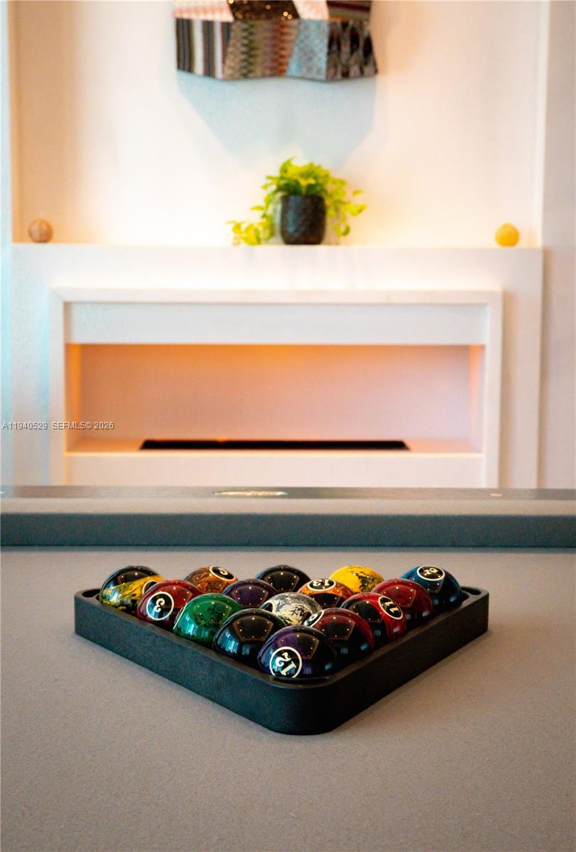 Billiard balls arranged in a tray on a counter, with a modern fireplace behind them.