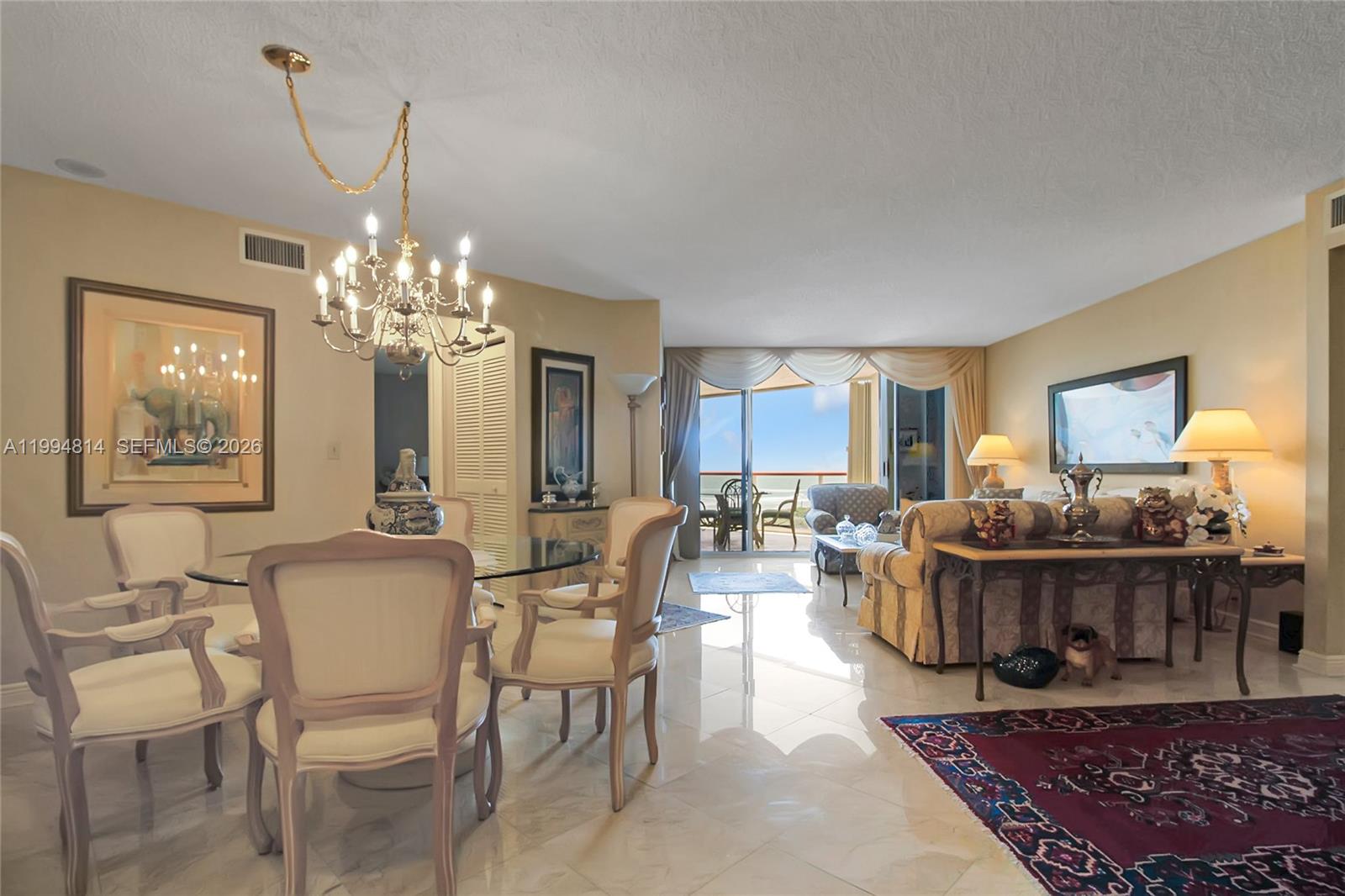 Furnished living and dining room with a chandelier and sliding doors to a balcony.