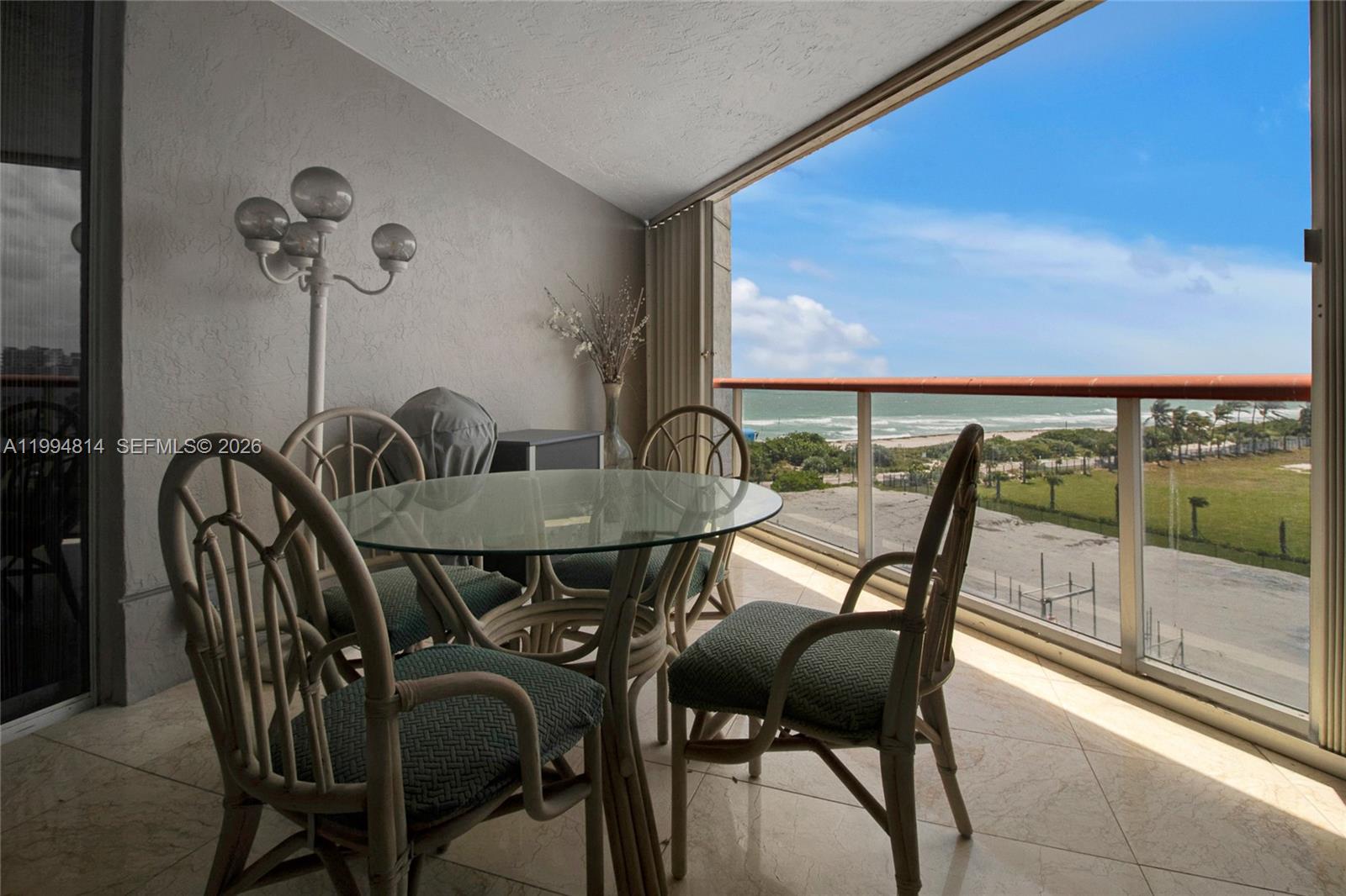 Furnished balcony dining area overlooking the ocean and beach.