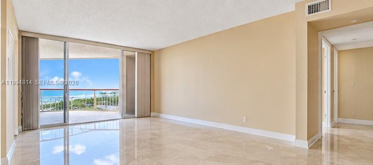 Vacant living room with glossy marble floors and sliding doors to a water-view balcony.