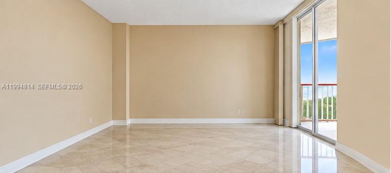 Vacant living room with glossy tile floors and sliding glass doors opening to a balcony.