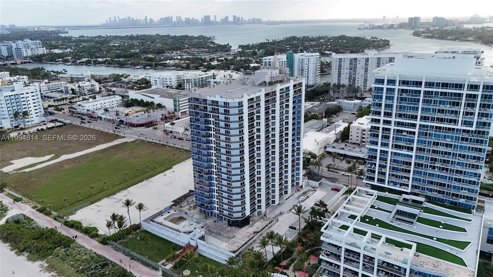 Beachfront condominium tower beside the shoreline, with bay water and the distant Miami skyline.