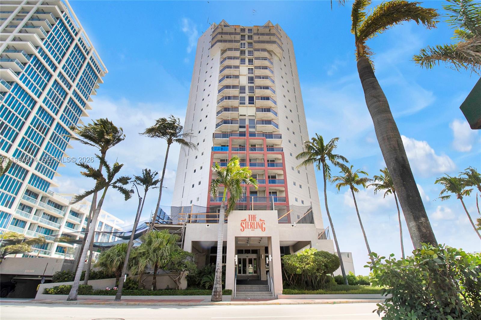 The Sterling condominium tower entrance, framed by palm trees and neighboring high-rises.