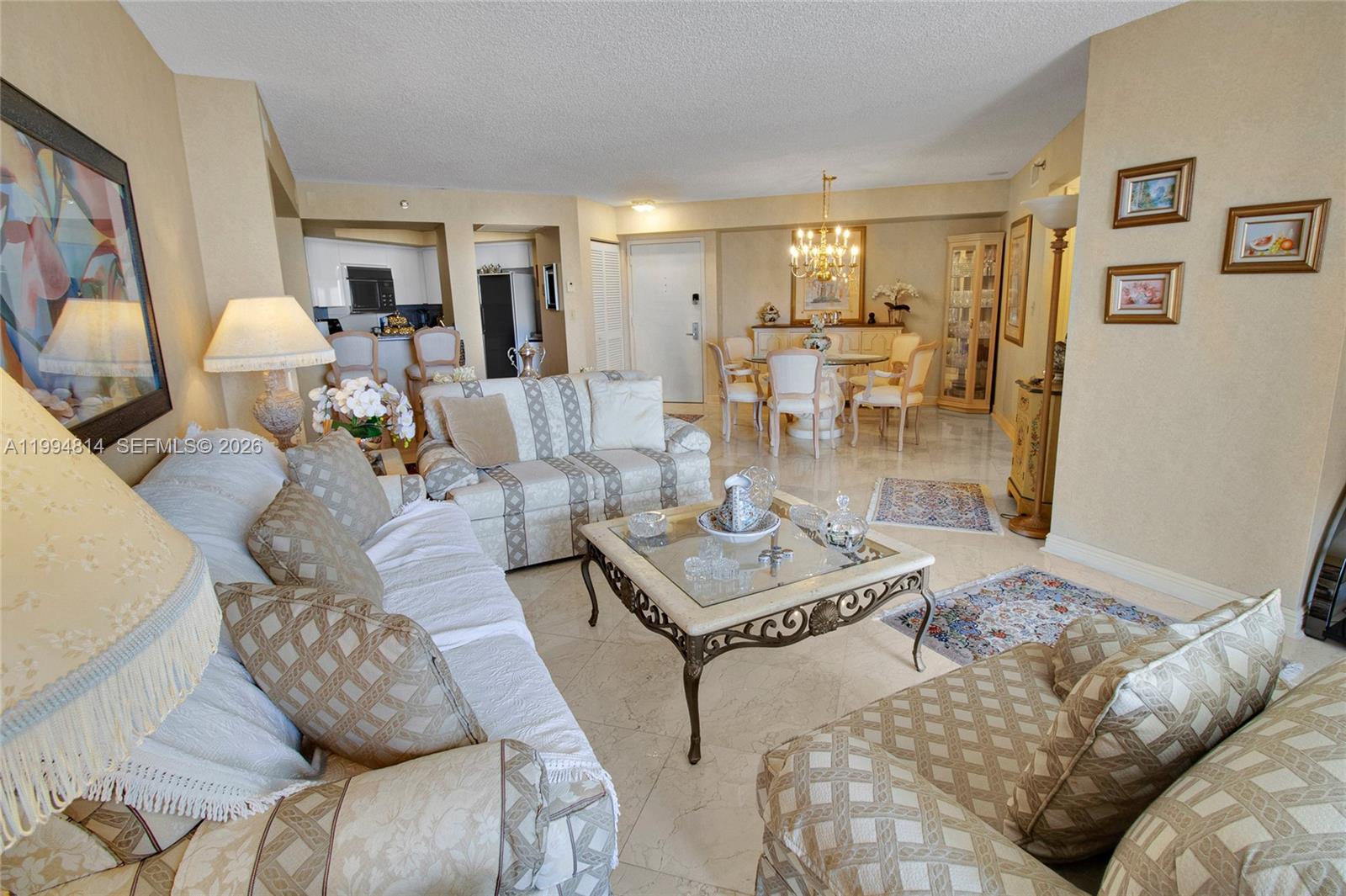 Furnished living room with patterned cream sofas, a glass-top coffee table, and an adjoining dining area.
