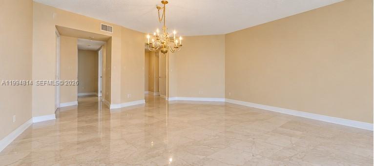 Vacant living area with glossy tile floors and a gold chandelier.