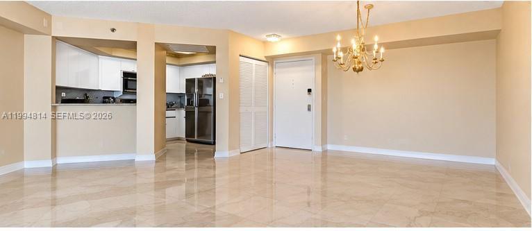 Unfurnished condo living and dining area with polished marble floors and a brass chandelier.