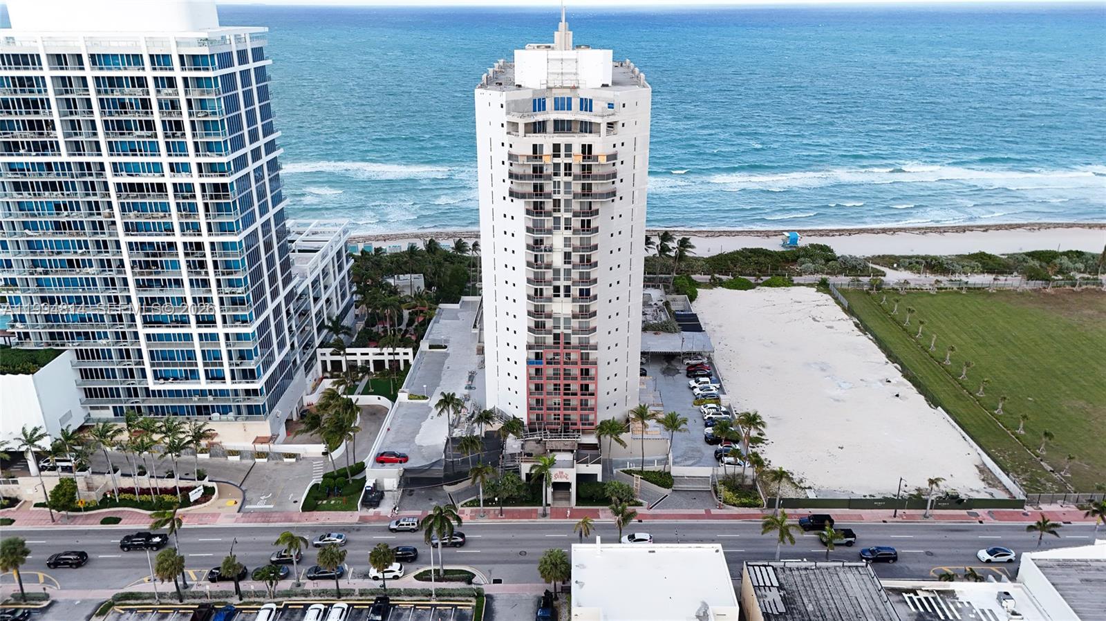 Oceanfront condominium tower beside the beach, neighboring high-rises, and Collins Avenue.