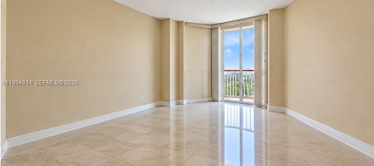 Empty living room with glossy tile floors and sliding doors opening to a balcony.