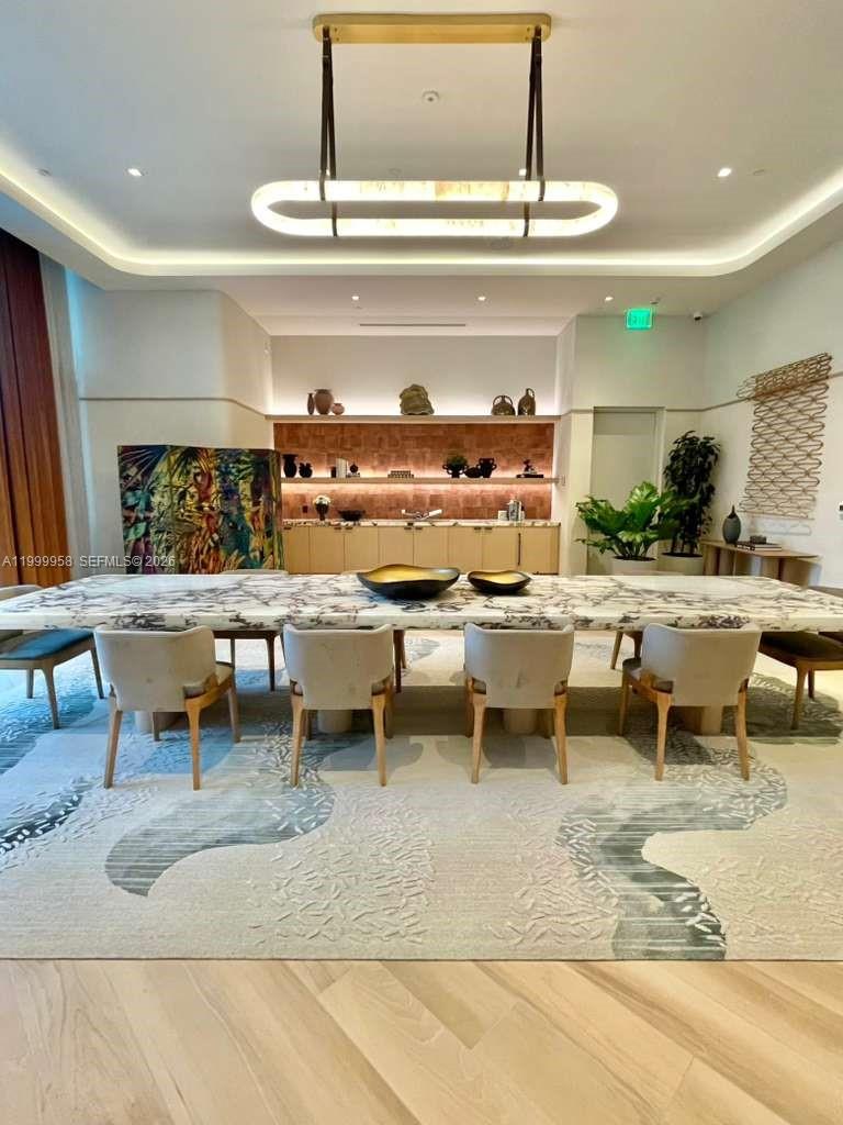 Dining area with a long marble table, upholstered chairs, and built-in display shelves.
