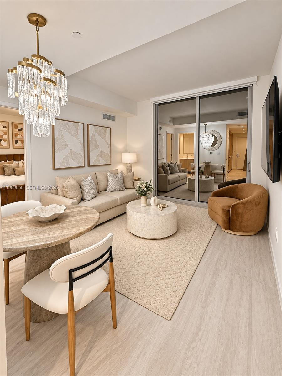 Living and dining area with a cream sofa, crystal chandelier, and round coffee table.