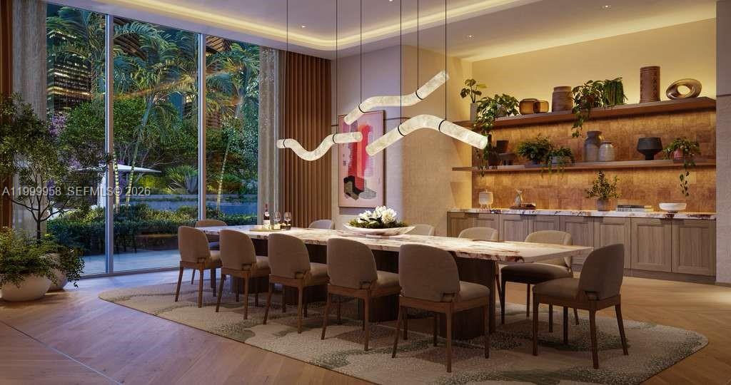 Dining room with a long marble table beside floor-to-ceiling windows overlooking greenery.