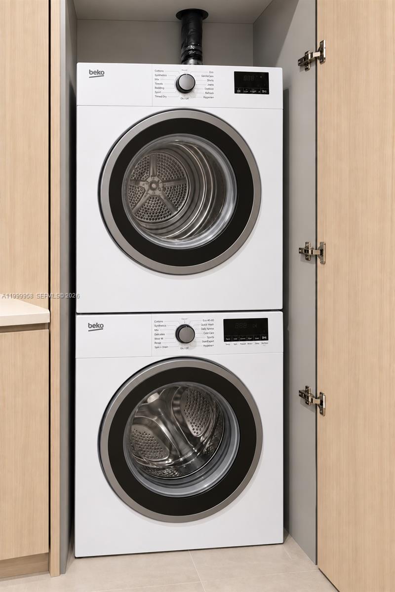 Stacked Beko washer and dryer tucked into a light wood cabinet.