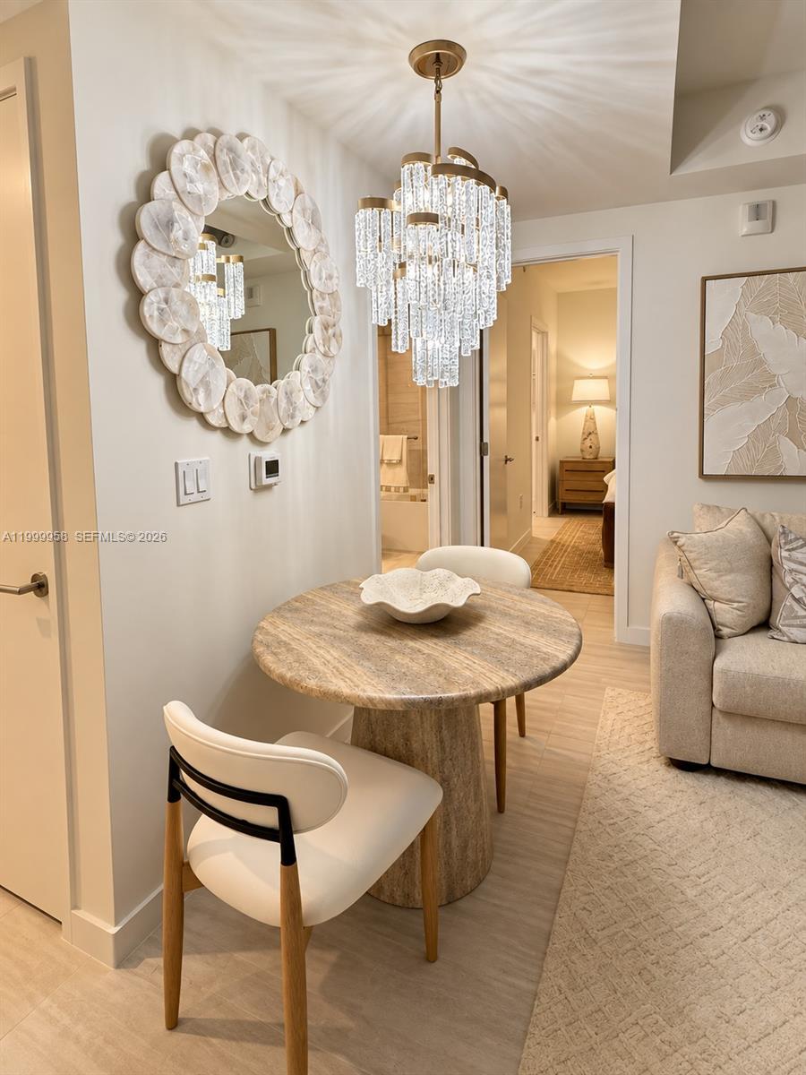 Dining nook with a round stone table, crystal chandelier, and decorative mirror.