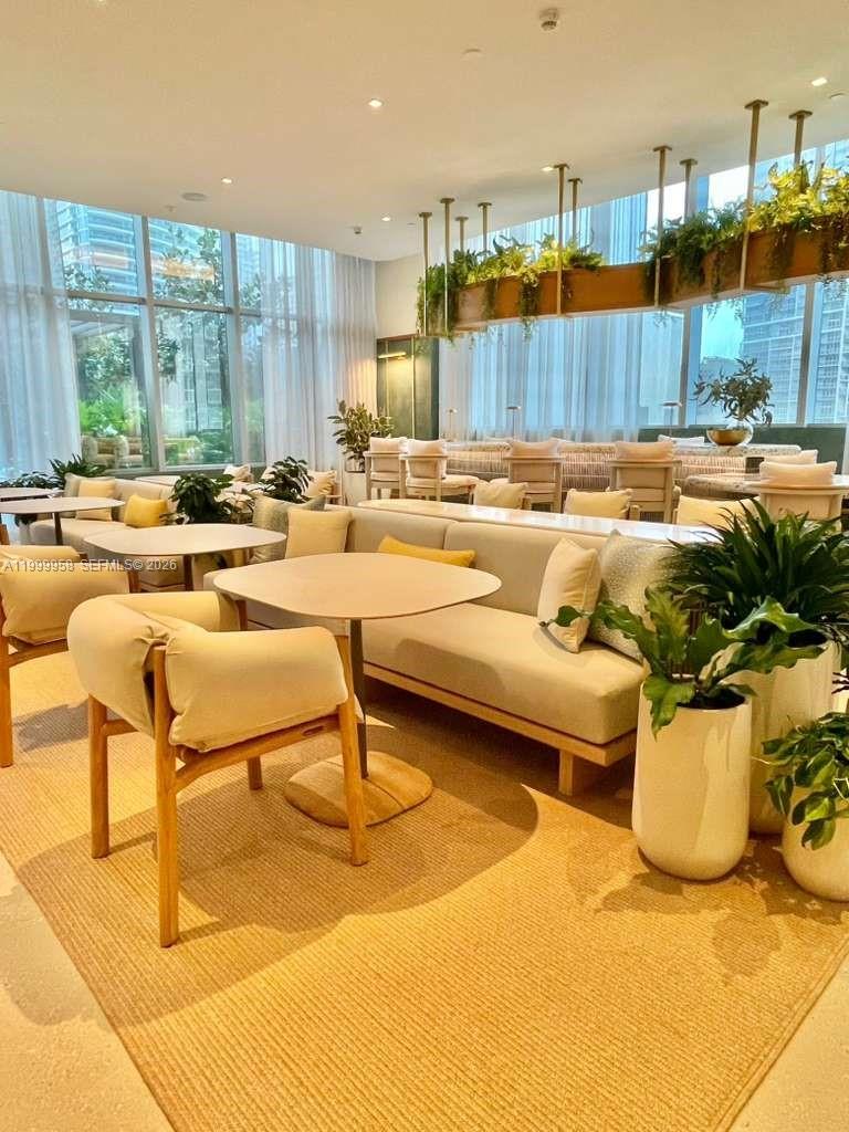 Condominium lounge with cream seating, potted plants, and floor-to-ceiling windows.