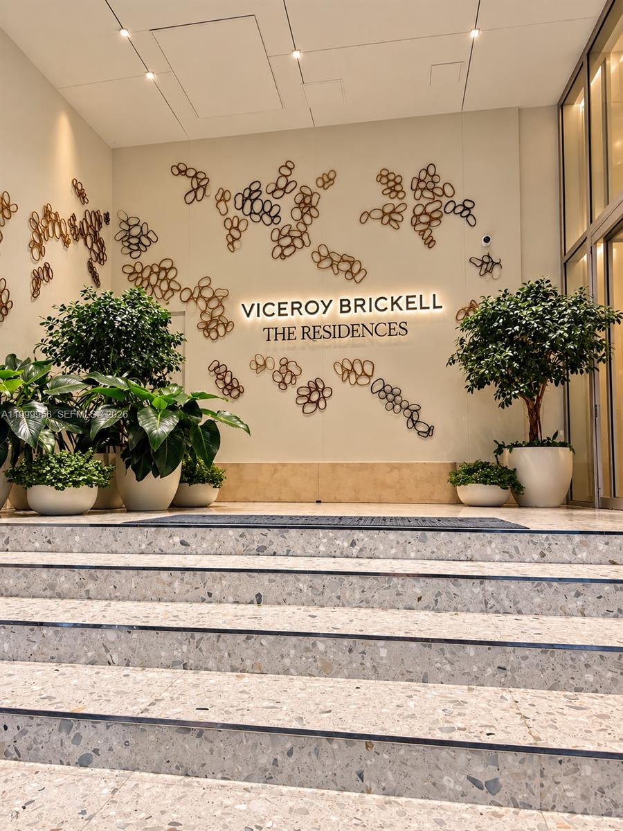 Viceroy Brickell lobby with terrazzo steps, potted plants, and sculptural wall art.