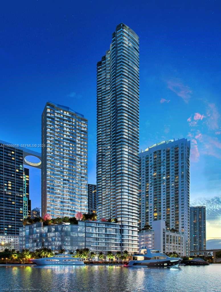 Waterfront condominium tower with curved balconies, neighboring high-rises, and boats along the water.