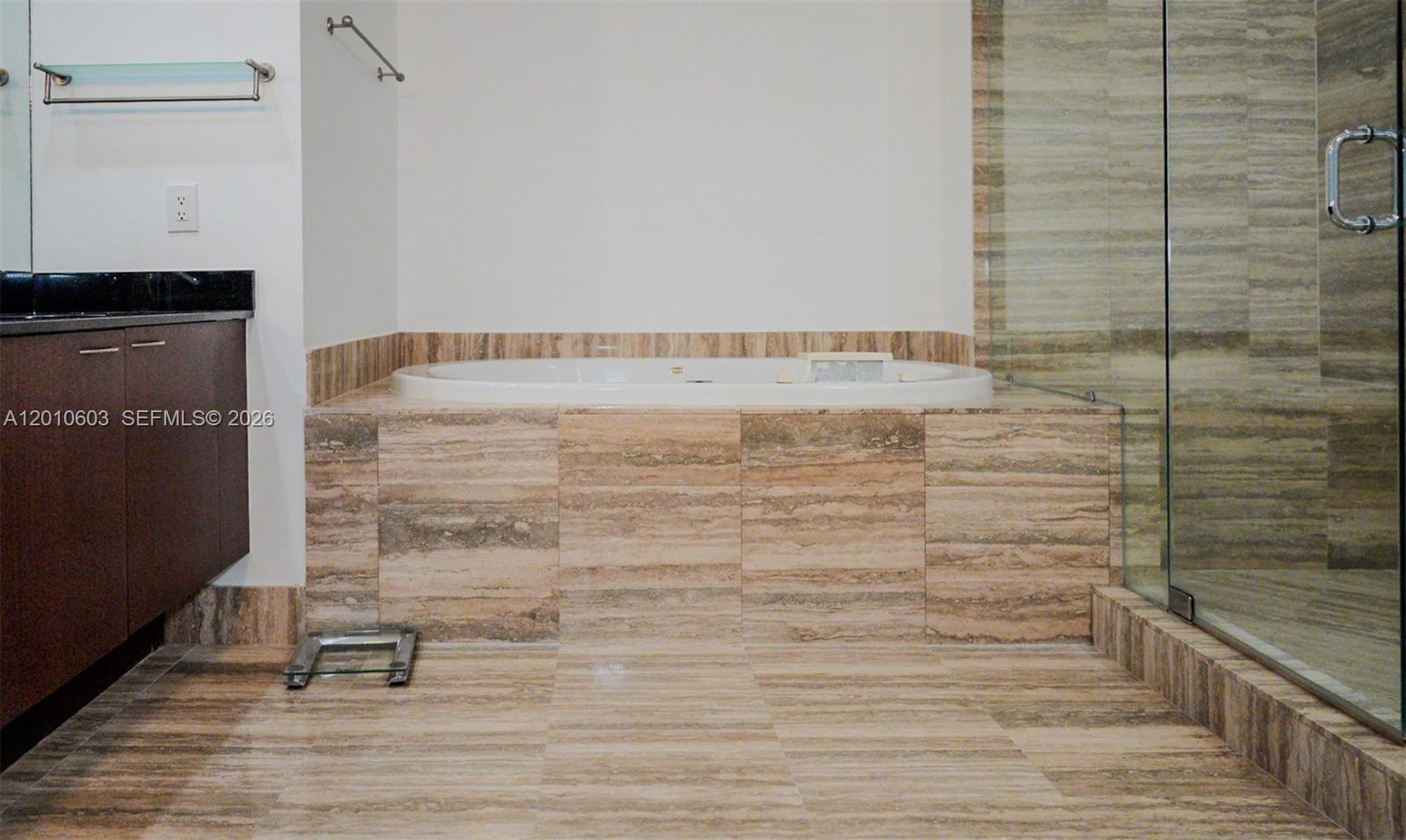 Bathroom with a stone-clad soaking tub beside a glass-enclosed shower.