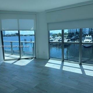 Vacant condo living area with marina views through large windows and sunlight across the tiled floor.