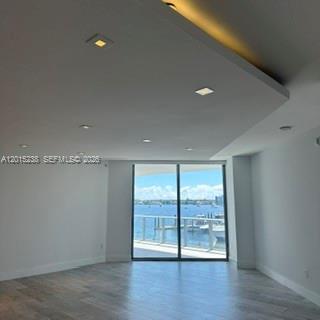 Empty apartment living area with wood-look floors and sliding doors to a water-view balcony.