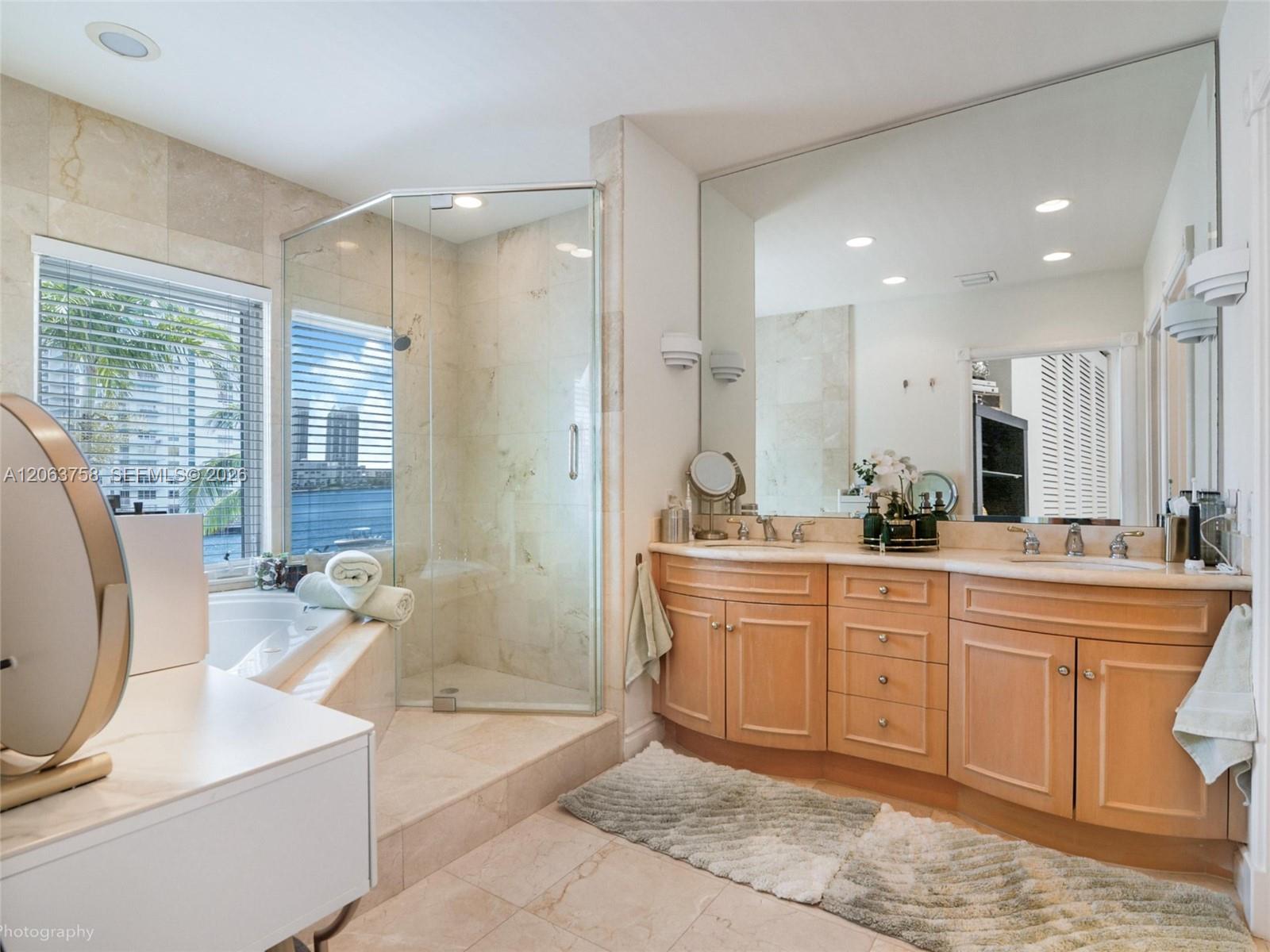 Bathroom with a glass shower, soaking tub beside windows, and a long wood vanity.