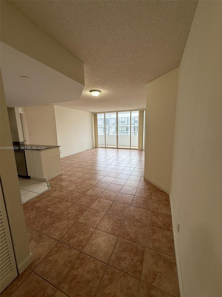 Vacant living area with reddish-brown tile floors and sliding glass doors to a balcony.