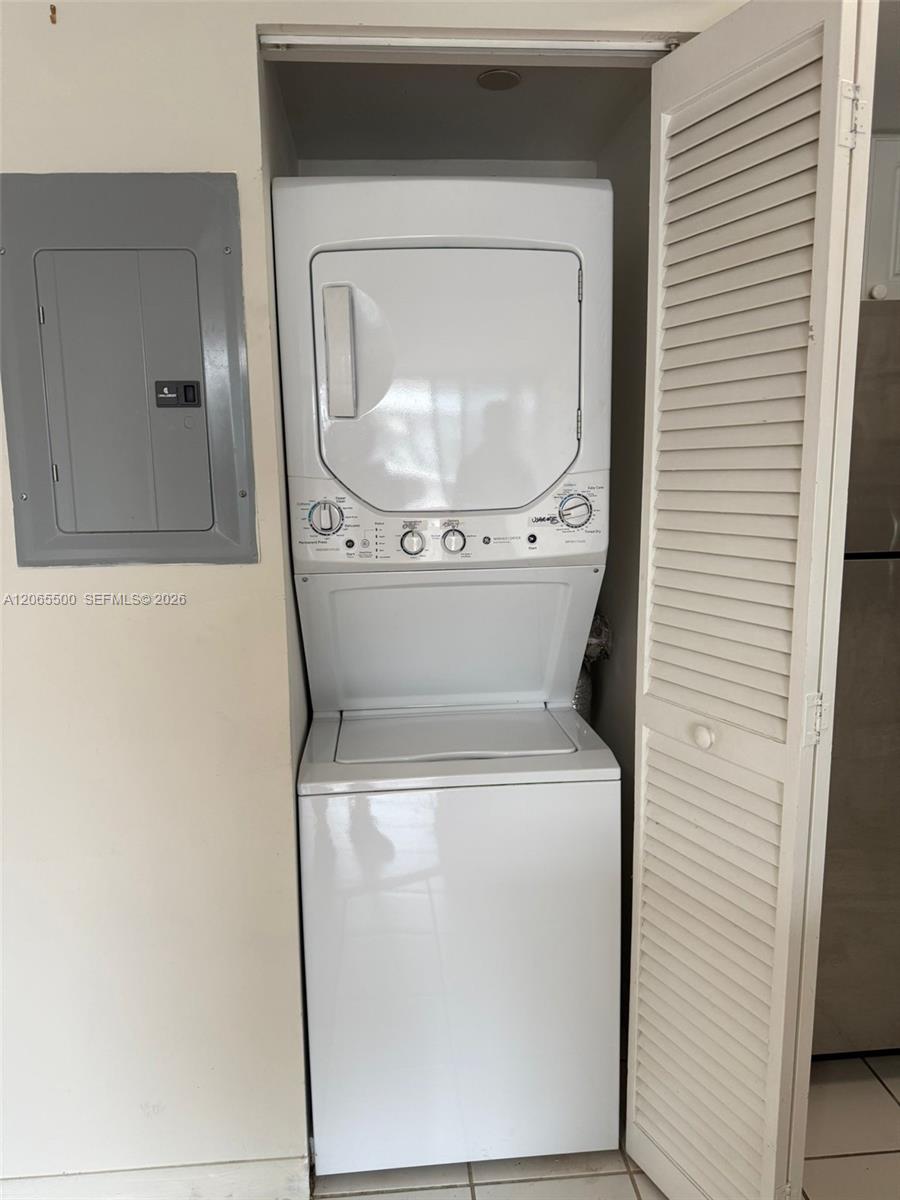 Stacked washer and dryer in a laundry closet with the louvered door open.