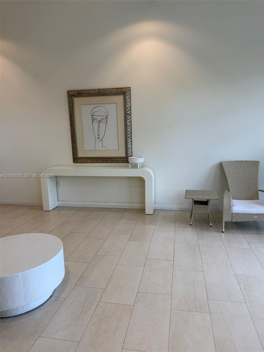 Tiled seating area with a white console, framed line art, and wicker chair.