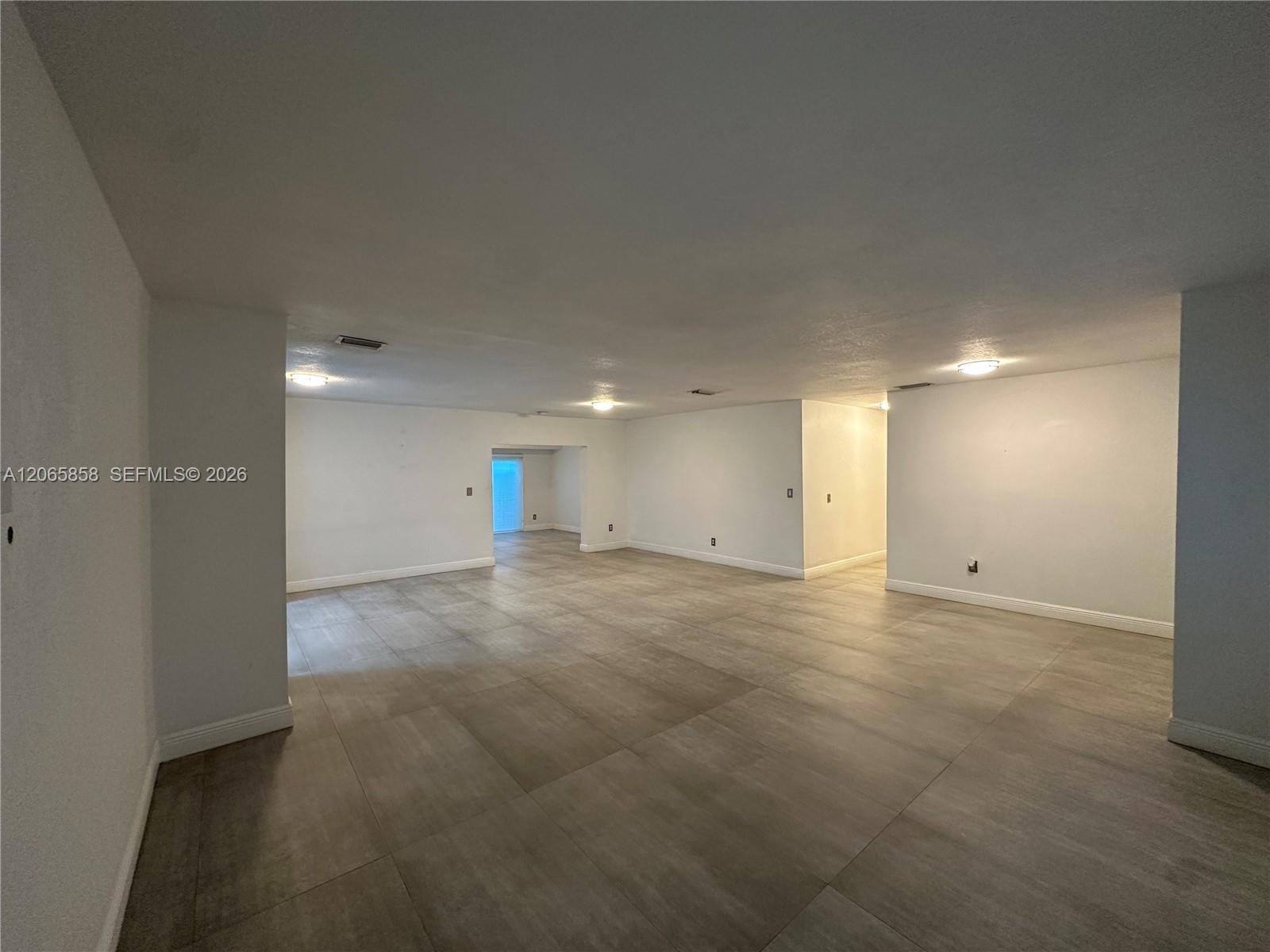 Vacant open-plan room with large gray tile flooring and light walls.