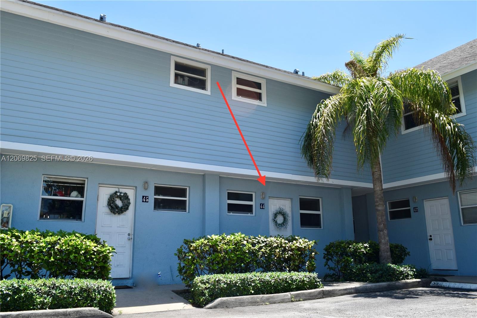 Blue two-story condominium exterior, with a red arrow pointing to the entrance marked 44.
