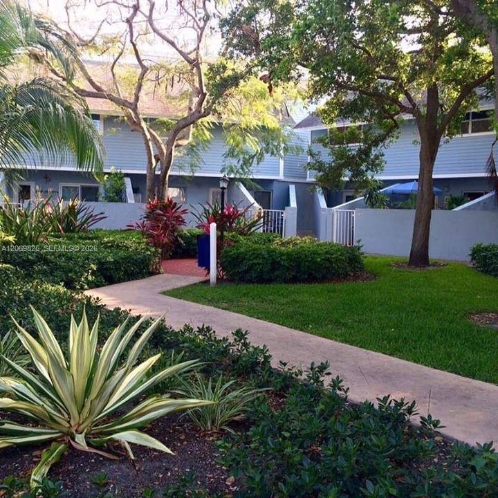 Blue residential building behind tropical landscaping and a curved walkway.