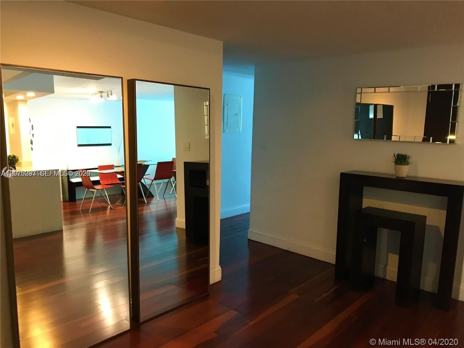 Living room with a geometric black fireplace, tall mirrors, and hardwood floors.