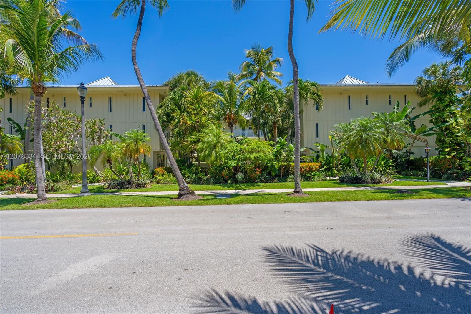 Cream-colored condominium exterior framed by palm trees and tropical landscaping.