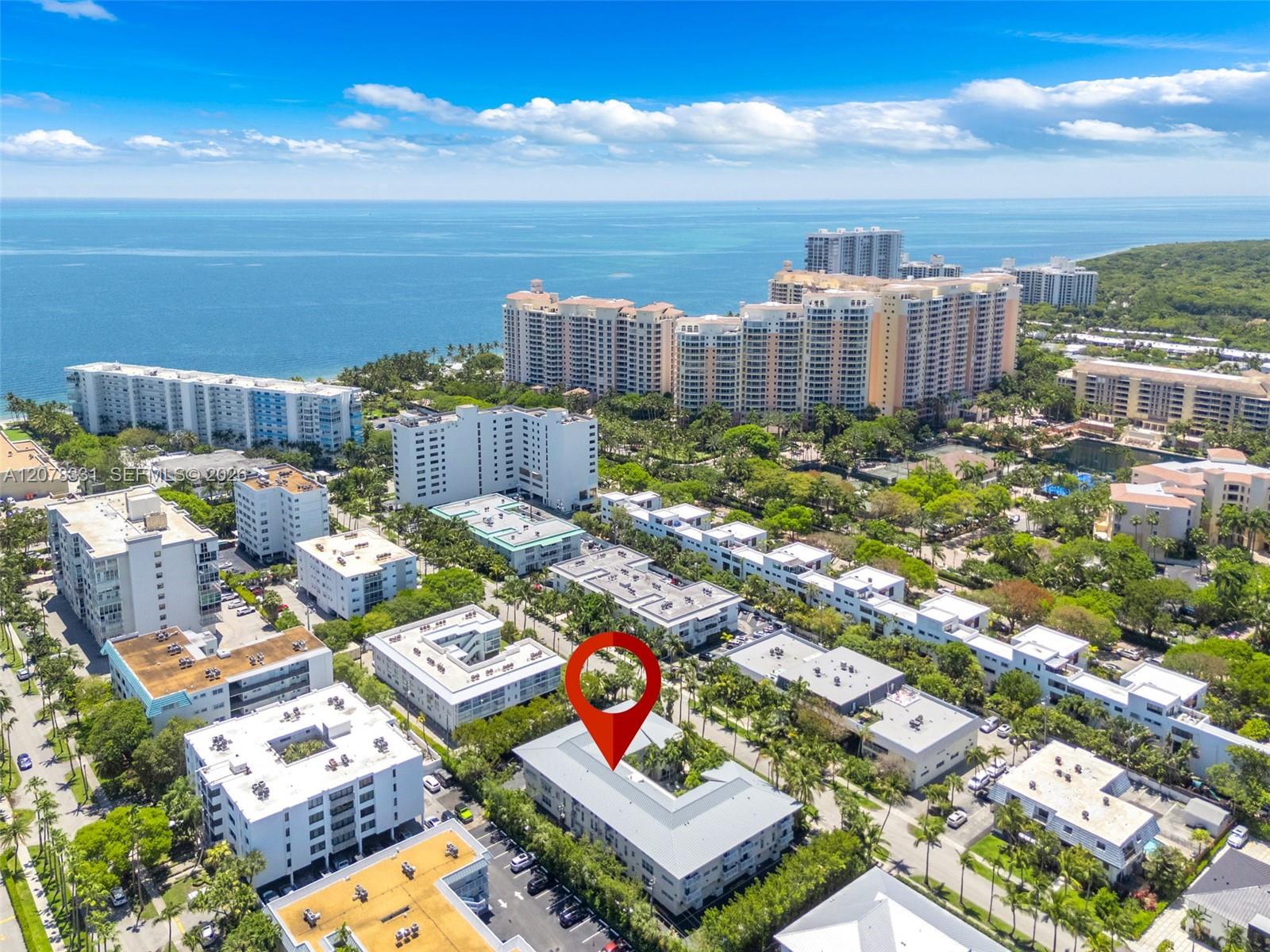 Aerial of Key Biscayne condos and ocean, with a red pin marking a low-rise building.