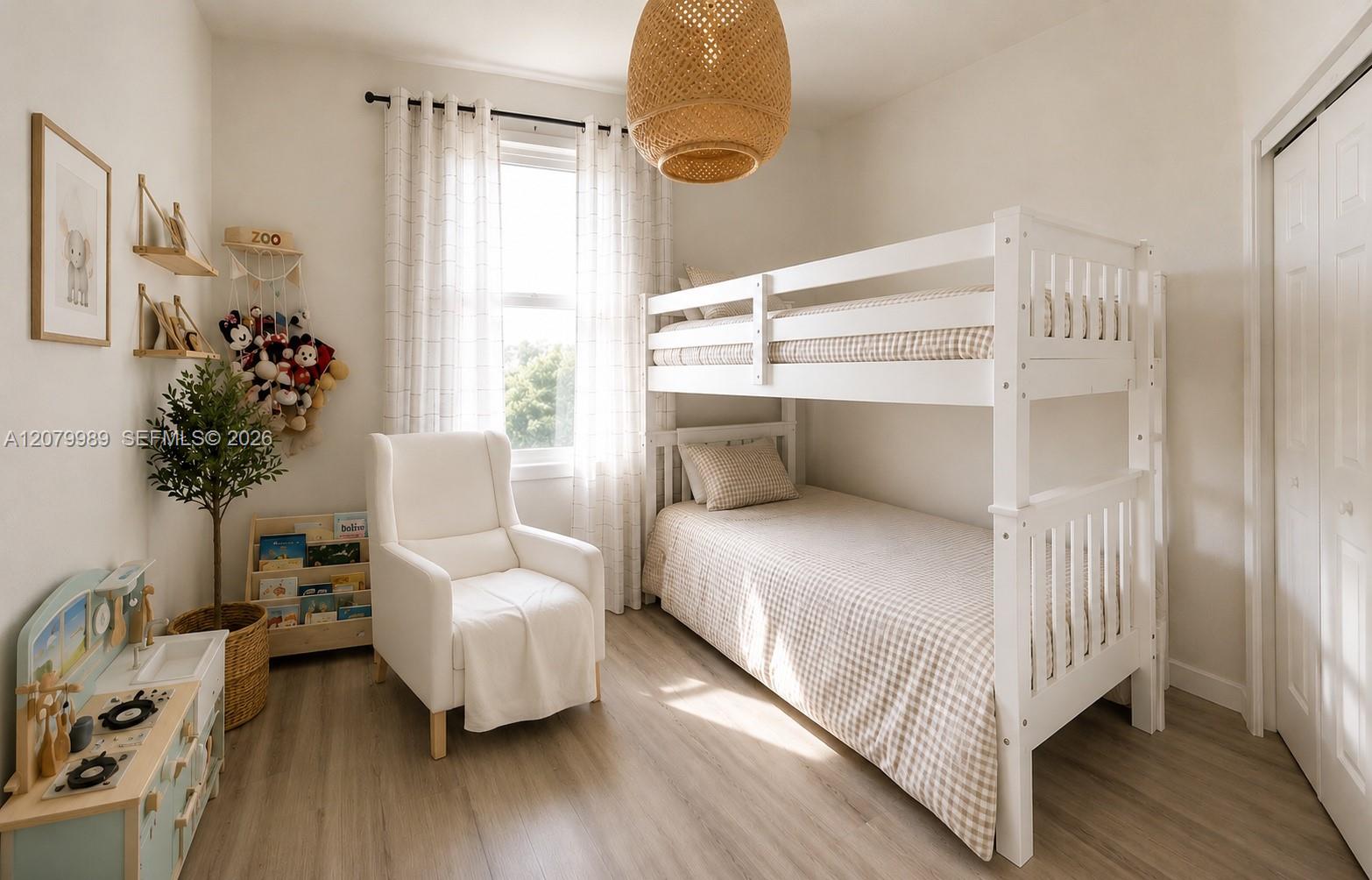 Furnished bedroom with a white bunk bed, armchair, children's toys, and a bright window.