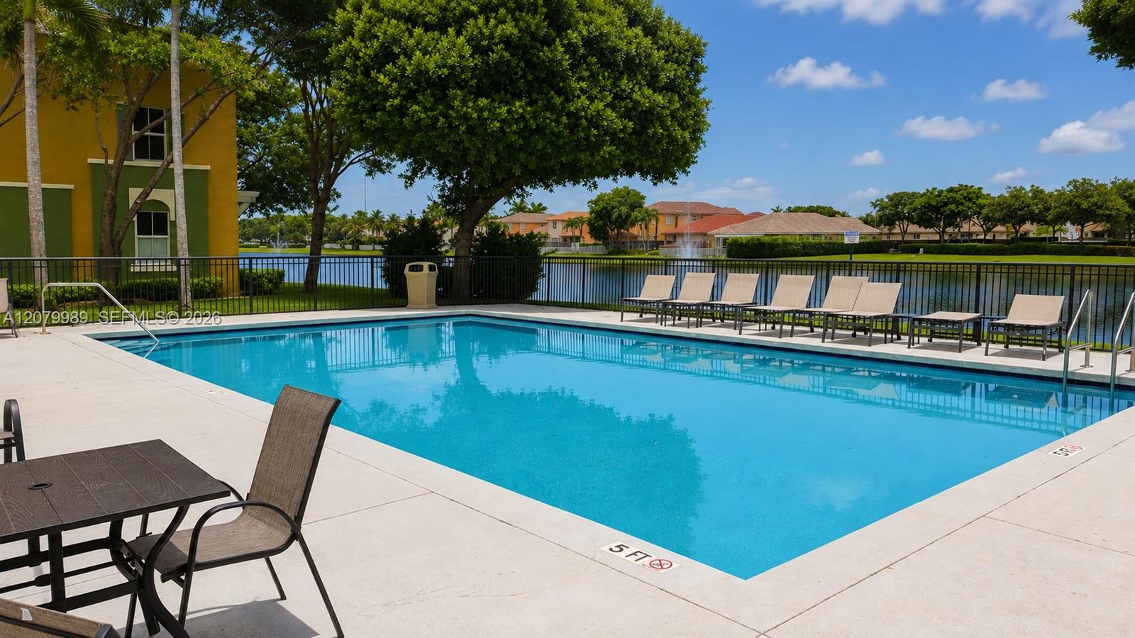 Community swimming pool beside a lake, with lounge chairs along the deck.