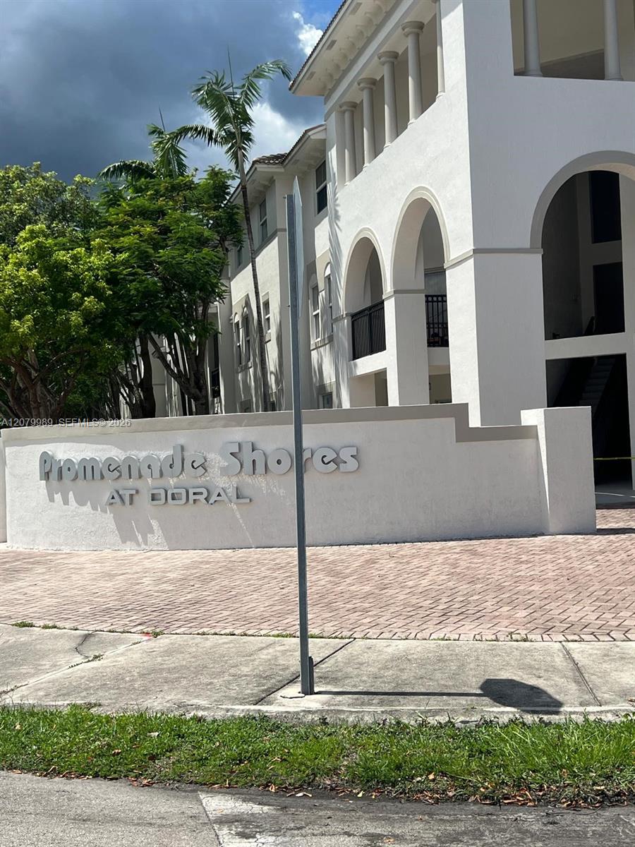 White condominium building with arched balconies and the Promenade Shores at Doral sign.