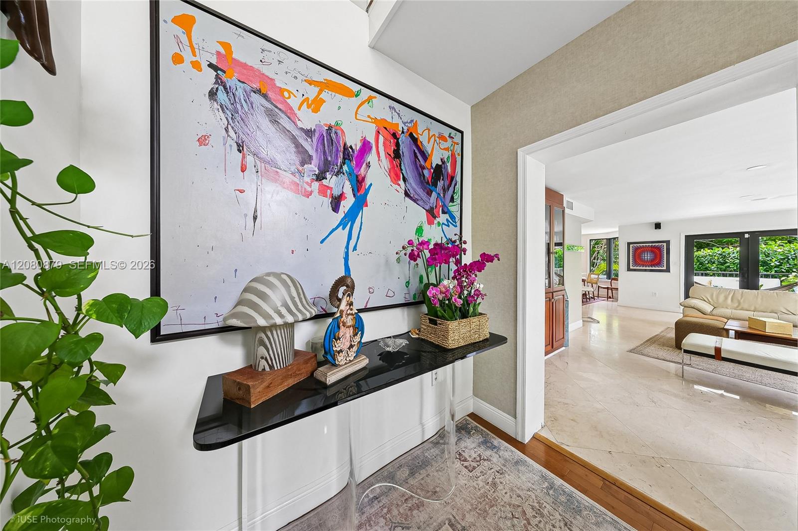 Entry hall with colorful abstract art above a console, looking through to a bright living room.