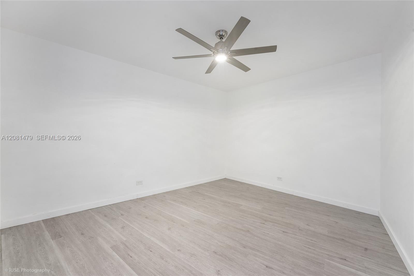 Empty room with gray wood-look flooring and a ceiling fan with light