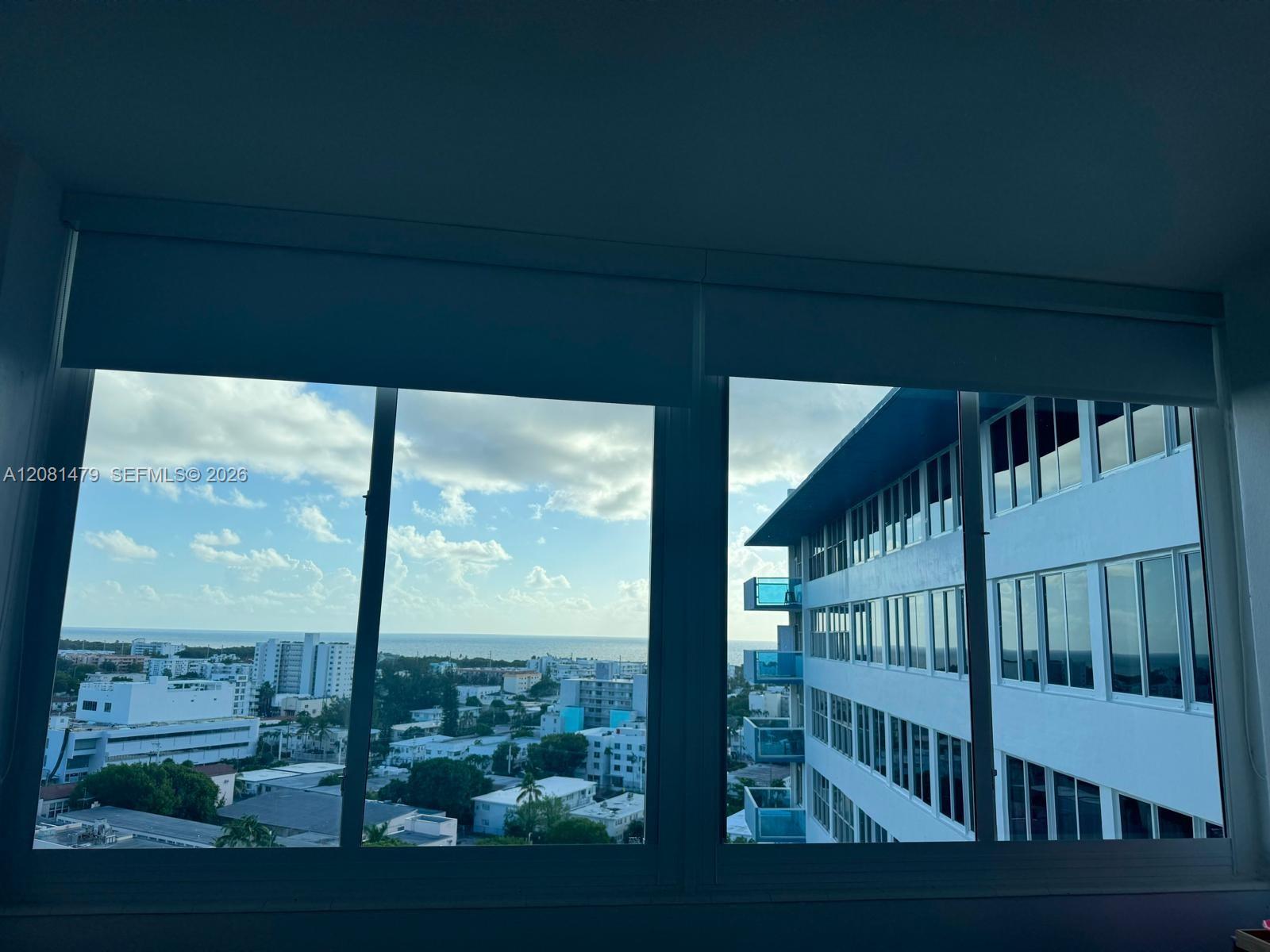 Ocean and city view through condo windows, with a neighboring high-rise nearby.