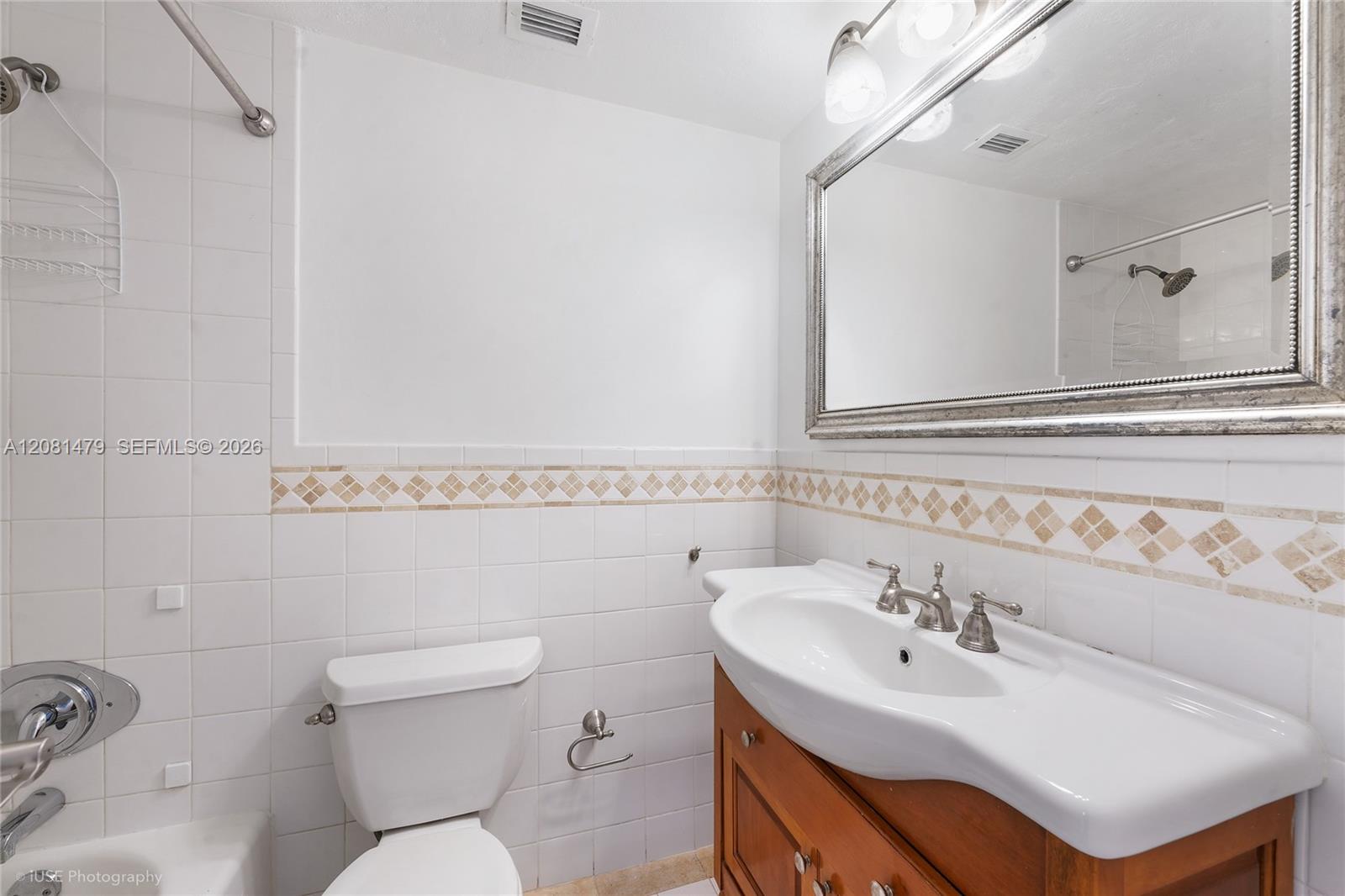 Bathroom with a wood vanity, large mirror, tiled shower, and bathtub.