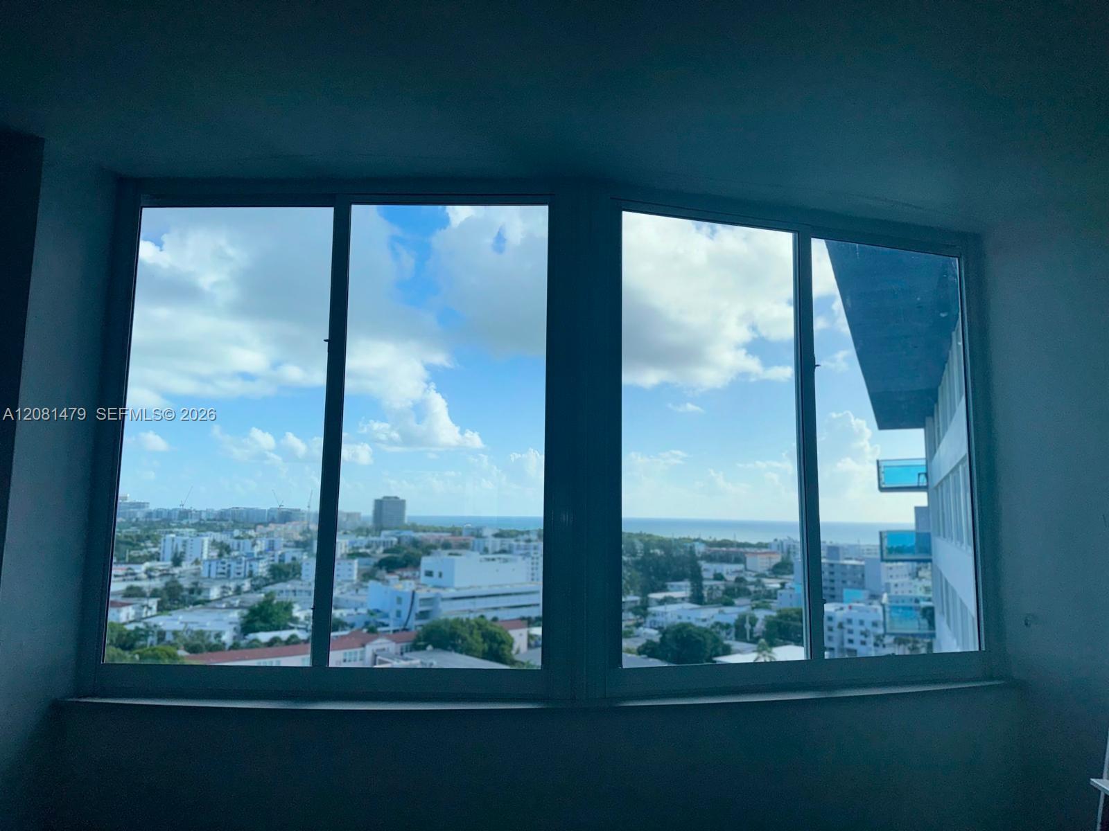 Large windows overlook Miami Beach buildings and the ocean from a vacant condo.