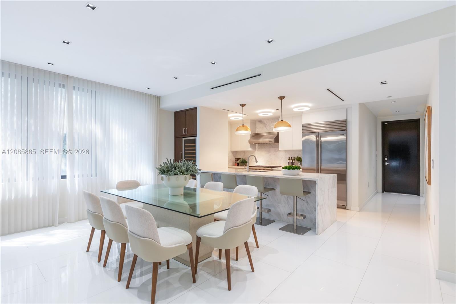 Modern kitchen and dining area with a marble island, stainless steel appliances, and a glass dining table.