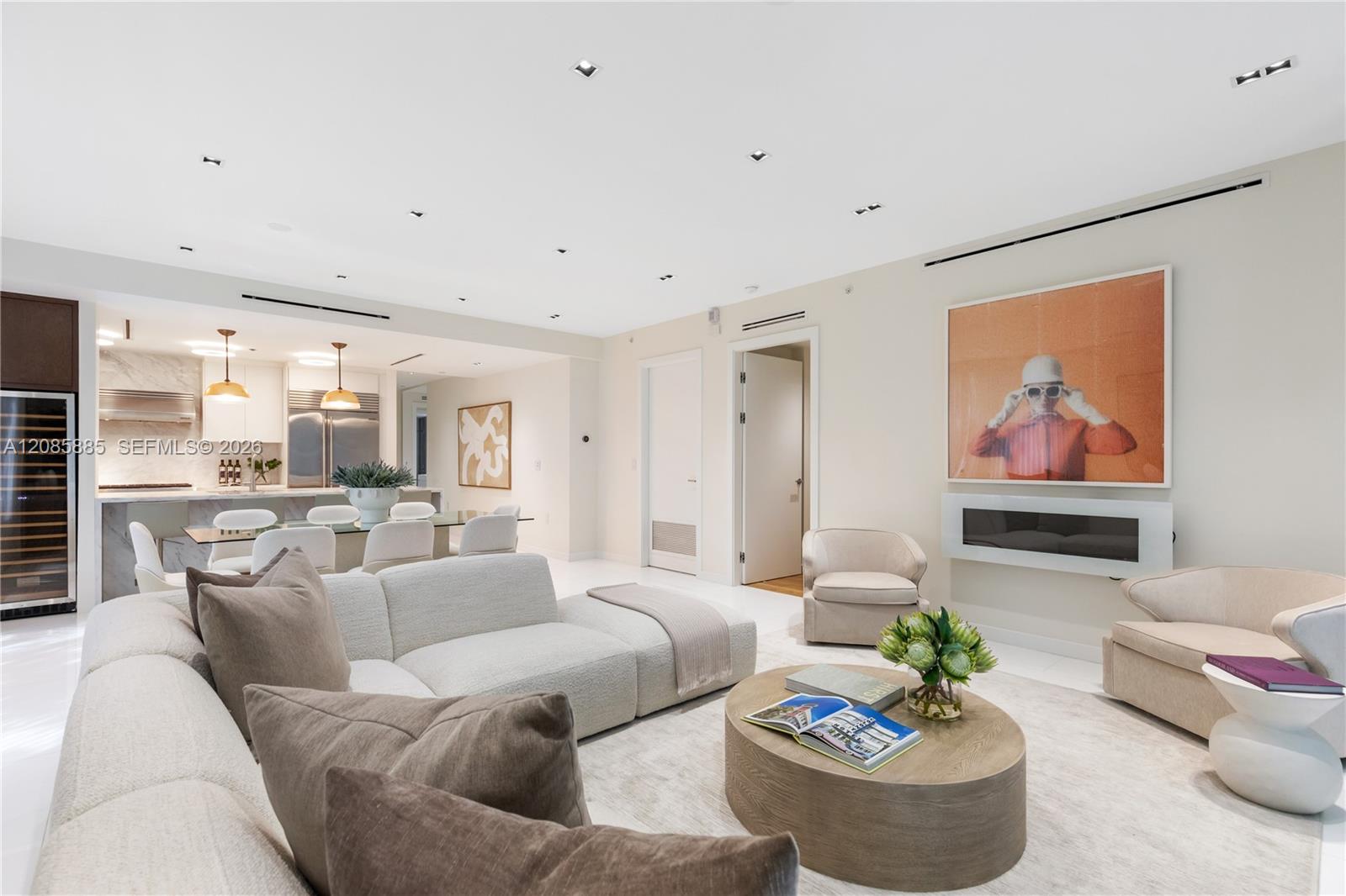 Furnished open-plan living room with a curved white sectional, round coffee table, and linear fireplace.