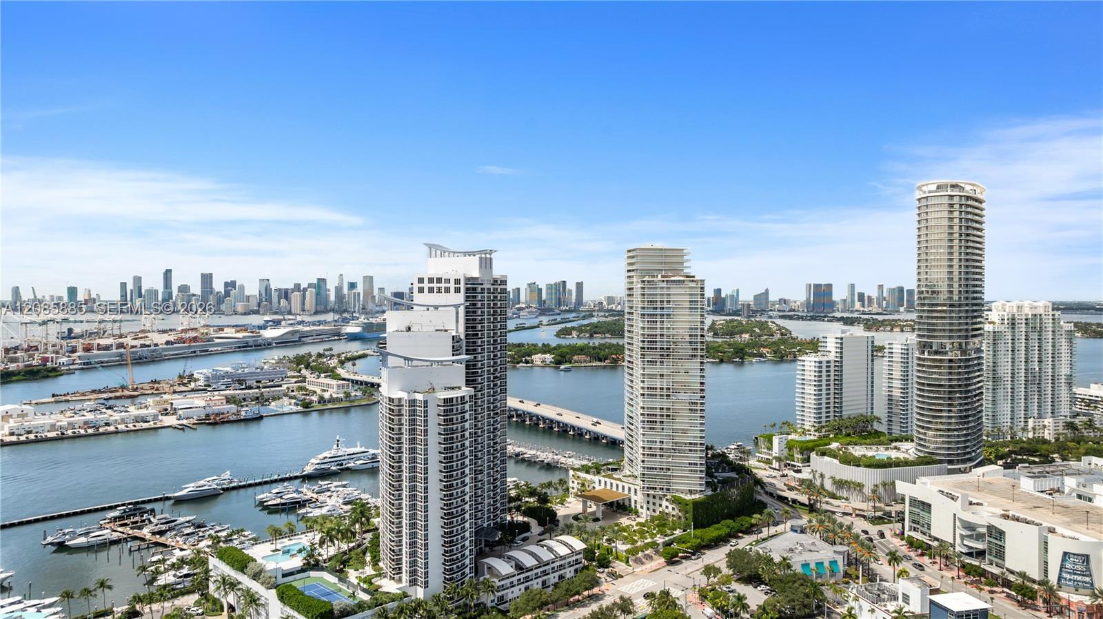 Miami skyline across Biscayne Bay, with waterfront towers, boats, and a bridge.