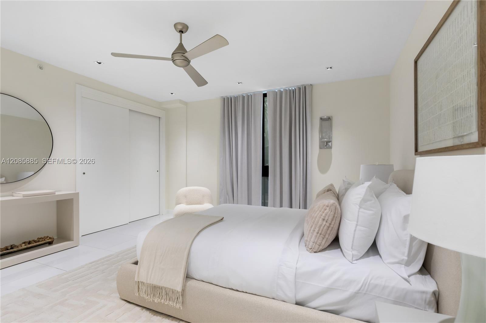 Furnished bedroom with a low upholstered bed, white bedding, and a ceiling fan.
